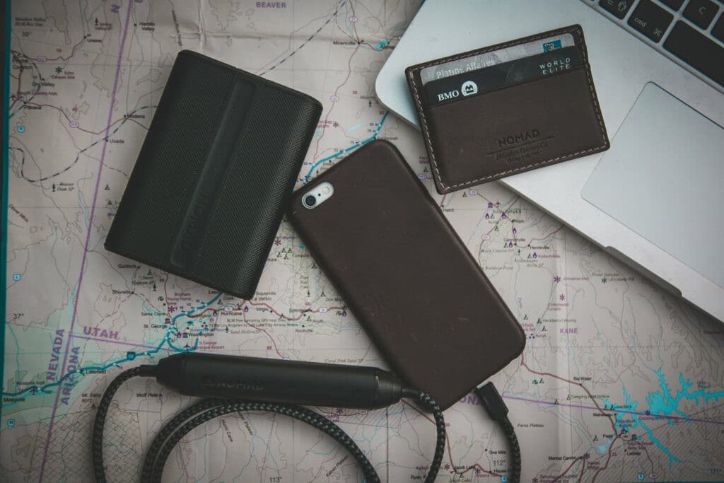 Cell phone, wallet, and chargers next to a map and computer