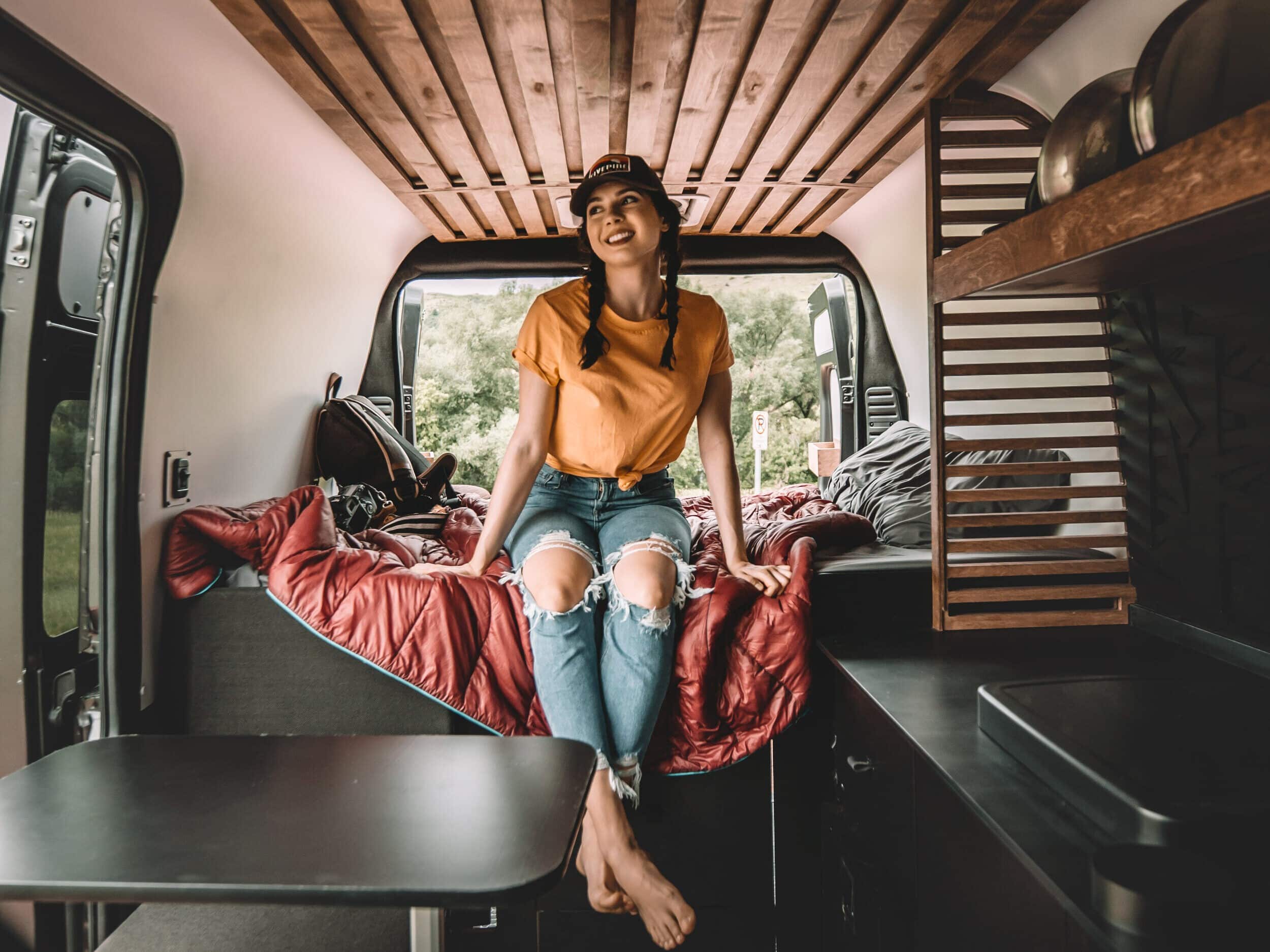 Person sitting on the bed in a Campervan Rental