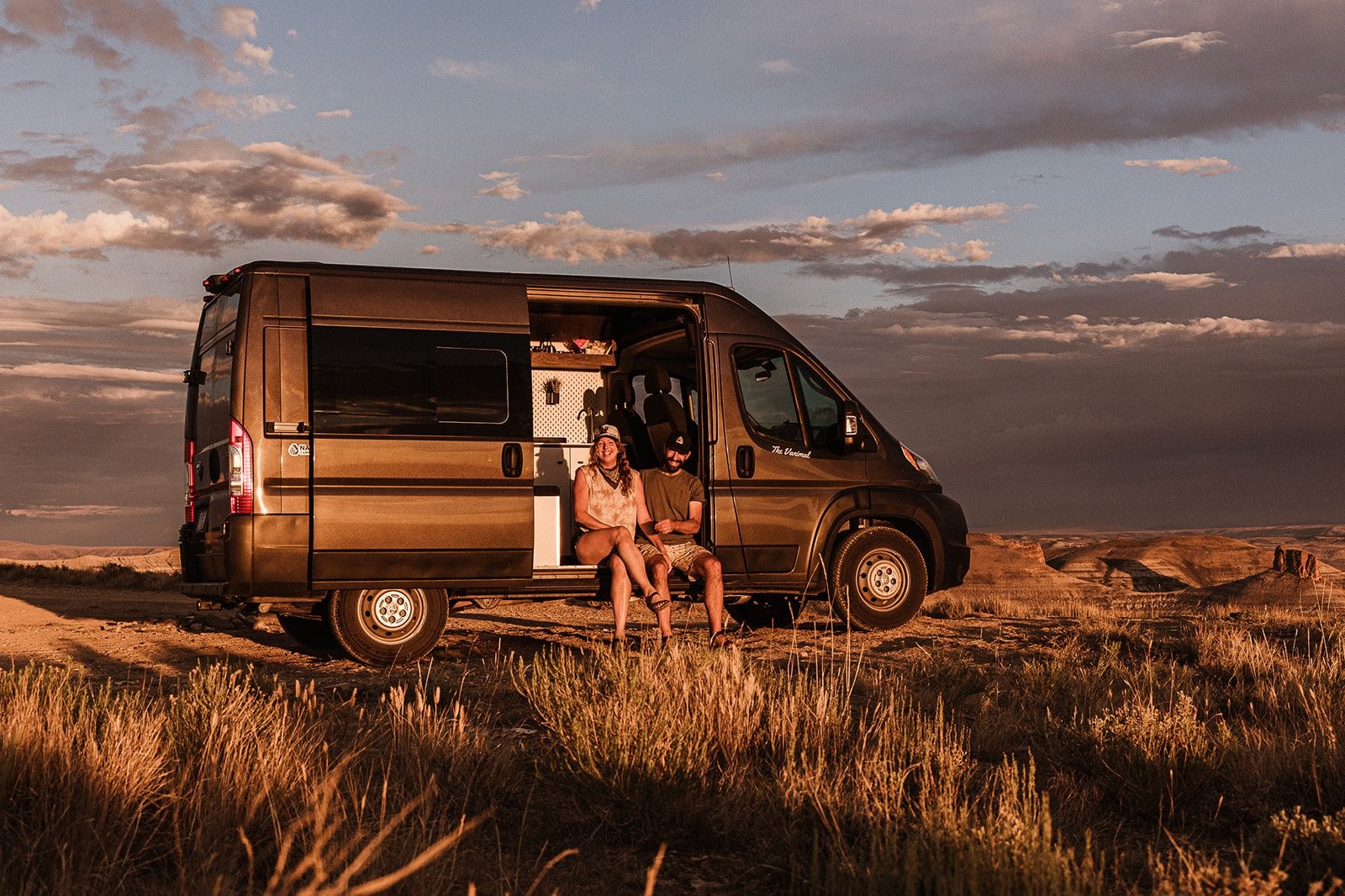 Couple sitting in a campervan at sunset